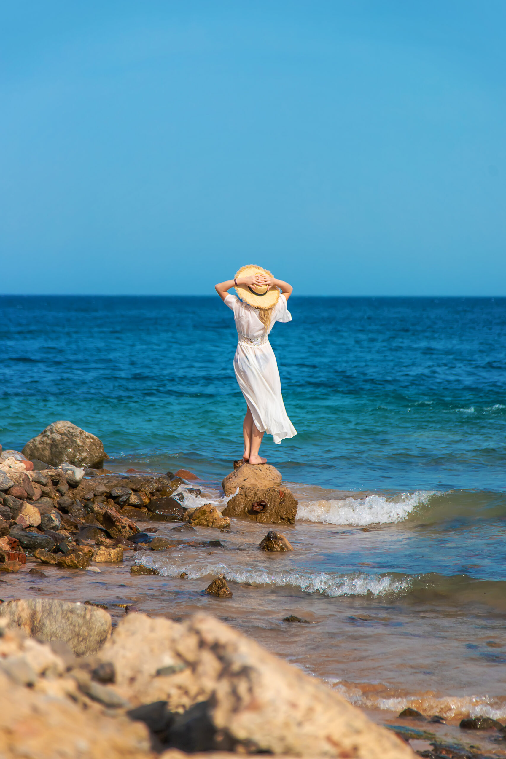 a woman in a hat looks at the sea. selective focus.